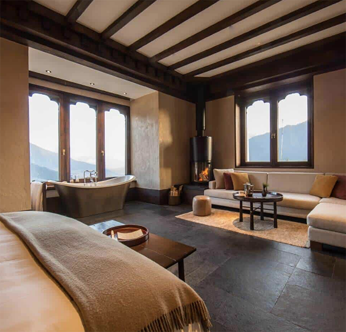 Schlicht eingerichtetes Schlafzimmer in der Gangtey Lodge mit einem großen Bett und warmen Farben