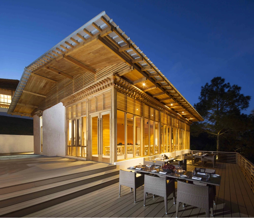 Außenansicht des Resorts bei Abenddämmerung mit beleuchteter Holzfassade und Terrass