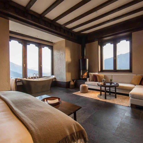 Schlicht eingerichtetes Schlafzimmer in der Gangtey Lodge mit einem großen Bett und warmen Farben