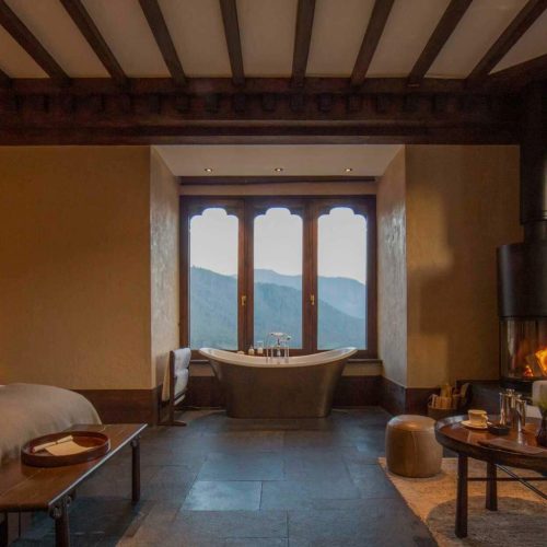 Gemütliches Gästezimmer in der Gangtey Lodge mit Holzmöbeln und Ausblick auf das Tal