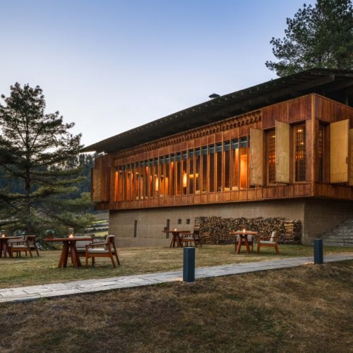 Blick auf die Amankora Gangtey Lodge eingebettet in grüne Hügel des Phobjikha-Tals.