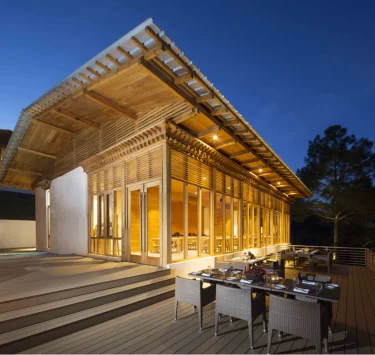 Außenansicht des Resorts bei Abenddämmerung mit beleuchteter Holzfassade und Terrass