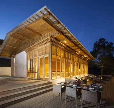 Außenansicht des Resorts bei Abenddämmerung mit beleuchteter Holzfassade und Terrass